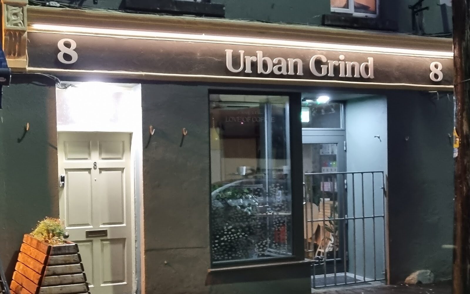 The Urban Grind shopfront at 8 William Street West, lit at night, with the name in raised letters on the fascia.